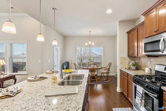 kitchen featuring backsplash, dark wood-style floors, brown cabinetry, stainless steel appliances, and a sink