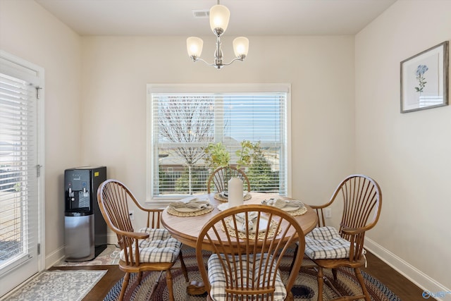 living area with baseboards, wood finished floors, visible vents, and a chandelier