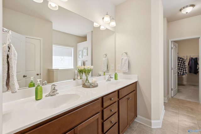 full bath featuring a sink, baseboards, double vanity, and tile patterned floors