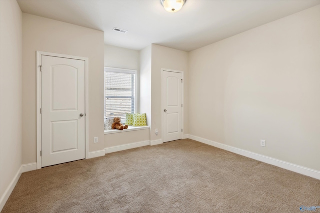 unfurnished bedroom with carpet flooring, baseboards, and visible vents