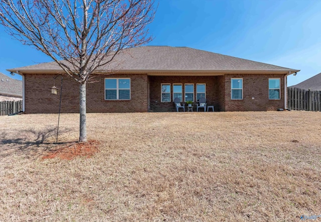 back of house featuring a yard, fence, and brick siding