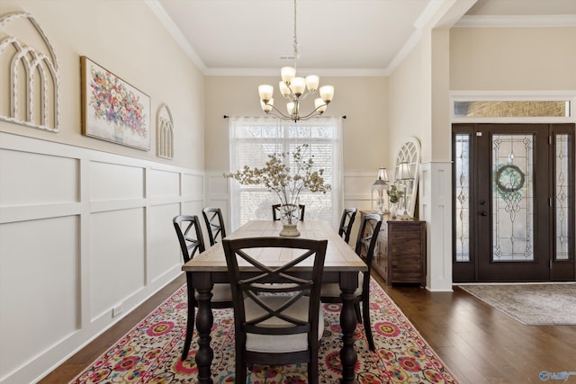 dining room featuring crown molding, a decorative wall, and a notable chandelier