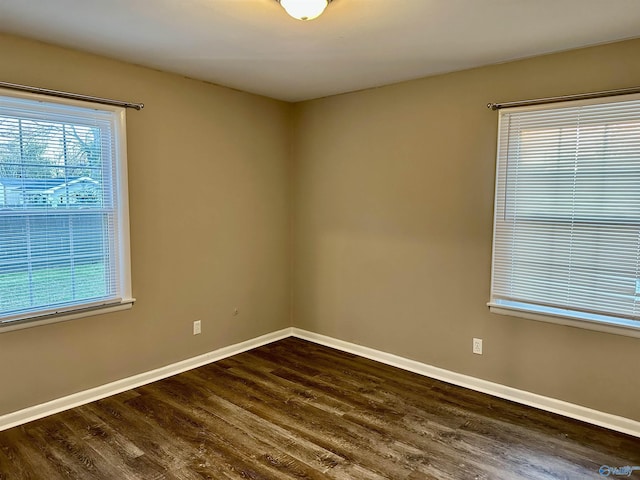 spare room featuring a healthy amount of sunlight and dark wood-type flooring