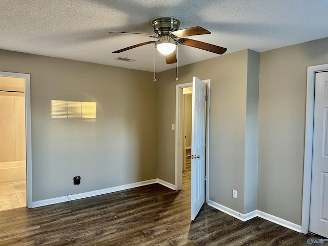 unfurnished bedroom featuring ensuite bathroom, dark hardwood / wood-style flooring, a textured ceiling, and ceiling fan