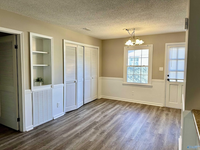 interior space featuring a textured ceiling, multiple closets, a chandelier, and hardwood / wood-style flooring