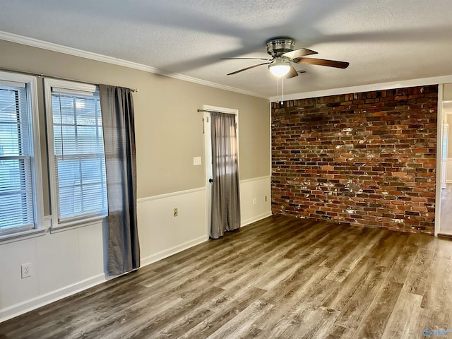 empty room featuring brick wall, a textured ceiling, ceiling fan, and ornamental molding