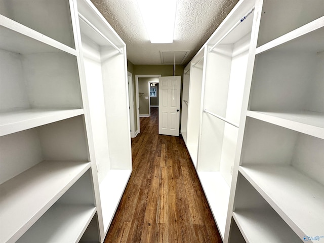 walk in closet featuring attic access and dark wood-style flooring