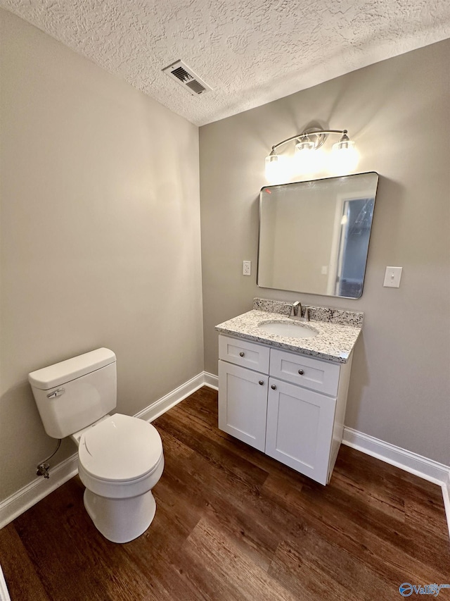 bathroom featuring vanity, wood-type flooring, a textured ceiling, and toilet