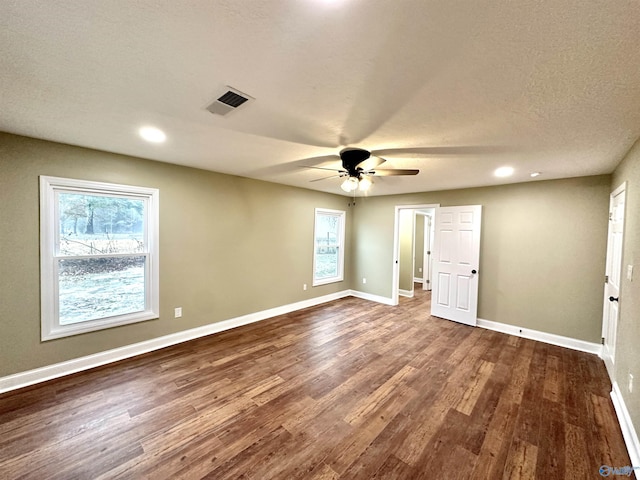 unfurnished bedroom featuring visible vents, dark wood-type flooring, baseboards, a textured ceiling, and a ceiling fan