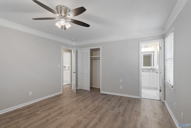 unfurnished bedroom with a closet, ornamental molding, connected bathroom, wood finished floors, and baseboards