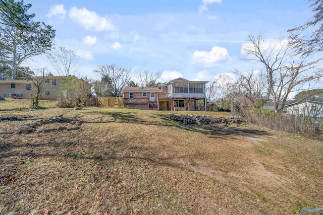 view of yard with stairs, a wooden deck, a sunroom, and fence