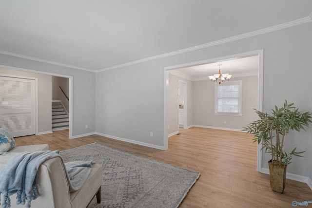 living area featuring light wood-style floors, a chandelier, crown molding, and baseboards