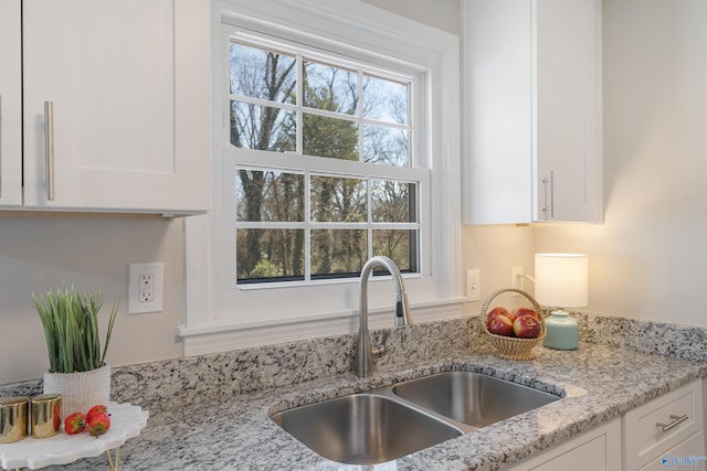 kitchen featuring a sink, light stone countertops, and white cabinets