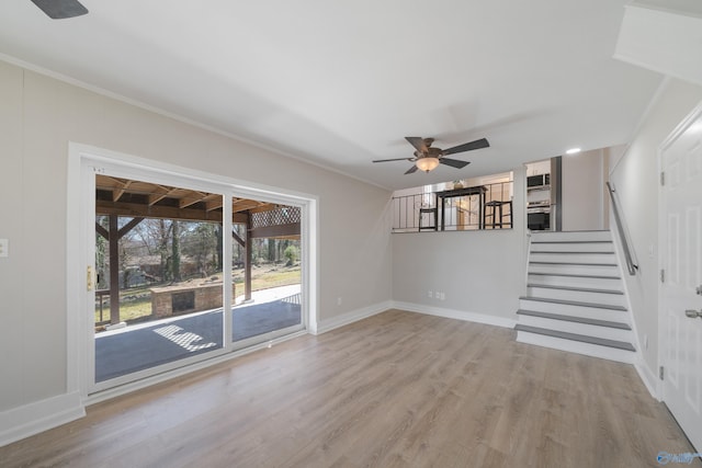 unfurnished living room featuring stairs, ornamental molding, baseboards, and wood finished floors