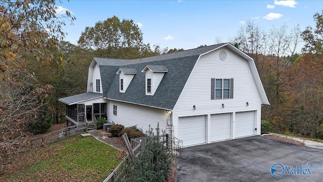 view of front of home with a sunroom, cooling unit, and a garage