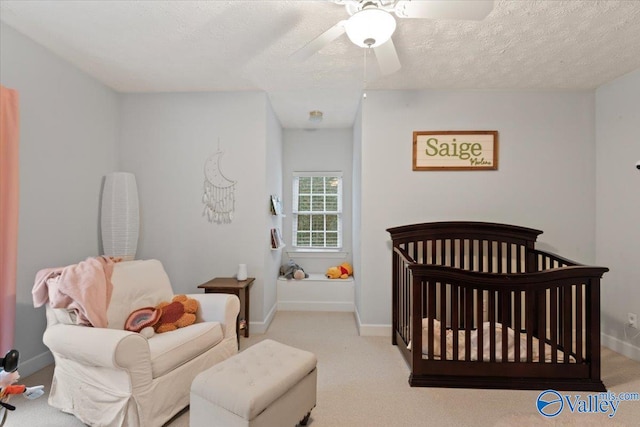 carpeted bedroom featuring a crib, a textured ceiling, and ceiling fan