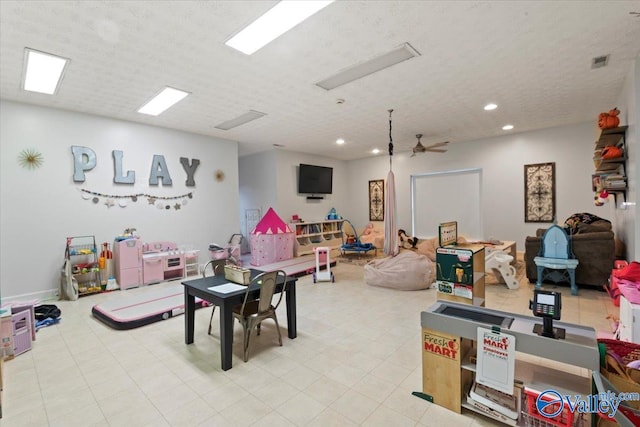 playroom with ceiling fan and a textured ceiling