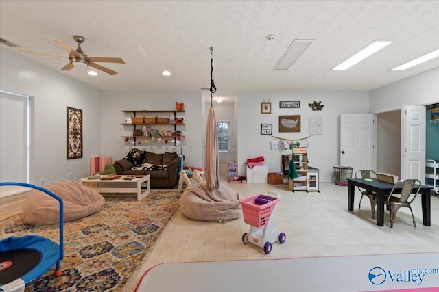 recreation room with ceiling fan, light tile patterned floors, and a textured ceiling