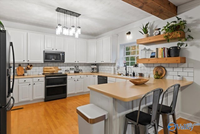 kitchen with kitchen peninsula, hanging light fixtures, white cabinets, and black appliances