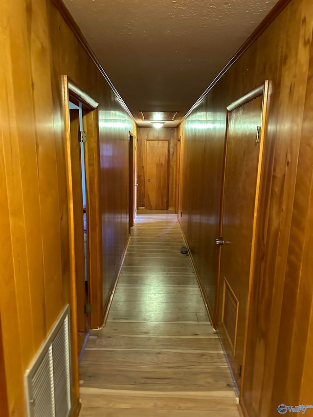 hallway featuring light hardwood / wood-style flooring, ornamental molding, and wooden walls