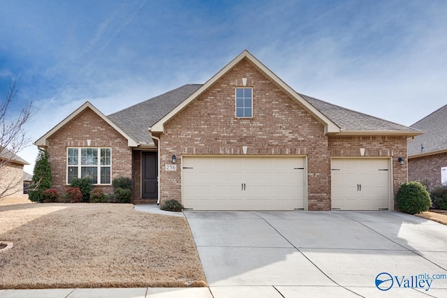 view of front of house featuring driveway, a shingled roof, and brick siding