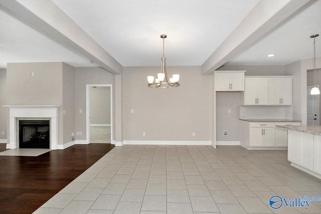 kitchen with an inviting chandelier, a fireplace with flush hearth, open floor plan, beamed ceiling, and baseboards