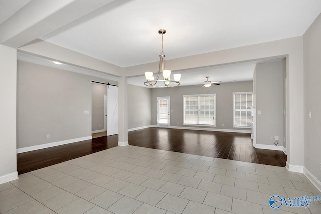 unfurnished room with ceiling fan with notable chandelier, a barn door, wood finished floors, and baseboards