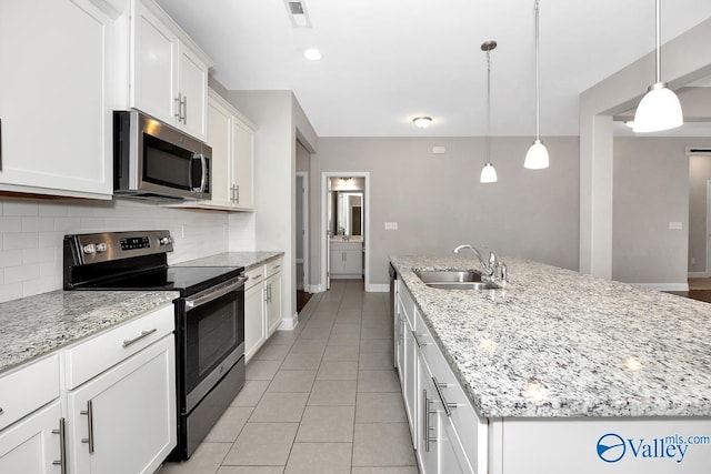 kitchen with a center island with sink, visible vents, decorative backsplash, appliances with stainless steel finishes, and a sink