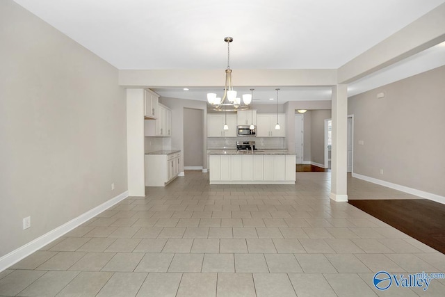 kitchen featuring baseboards, appliances with stainless steel finishes, open floor plan, and backsplash