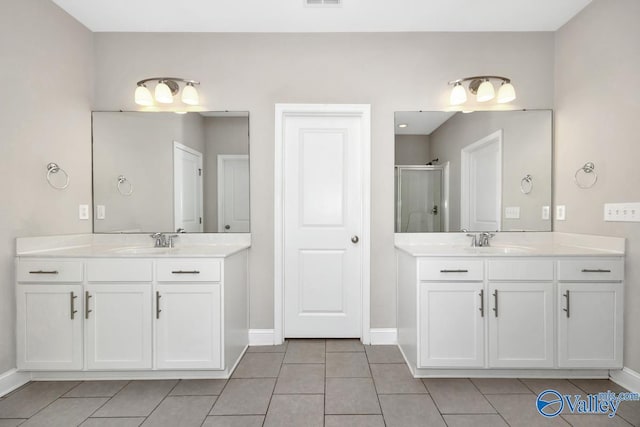 bathroom featuring a shower stall, two vanities, and a sink