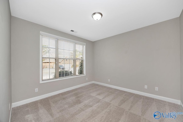 spare room featuring light carpet, visible vents, and baseboards