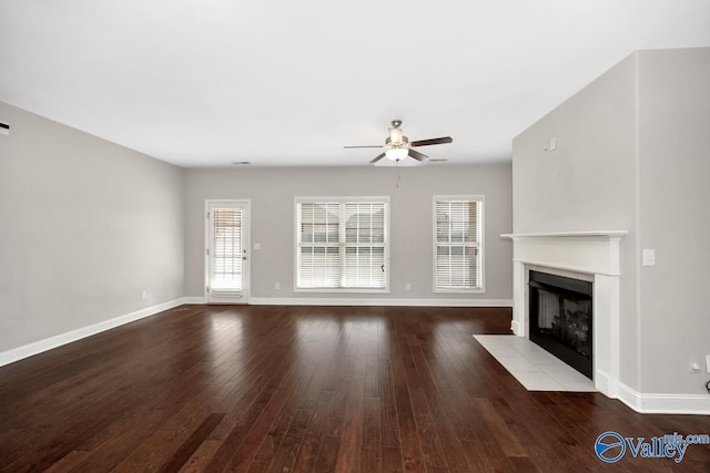 unfurnished living room featuring ceiling fan, a fireplace with flush hearth, hardwood / wood-style flooring, and baseboards