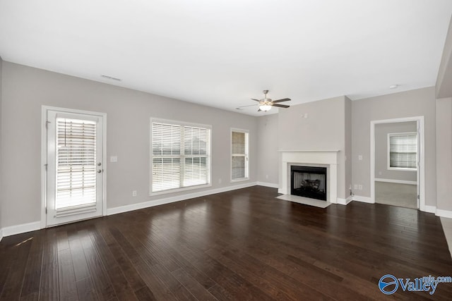unfurnished living room with a fireplace with flush hearth, wood finished floors, a ceiling fan, and baseboards
