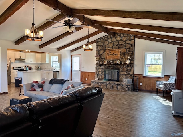 living room with dark wood finished floors, ceiling fan with notable chandelier, wainscoting, and a fireplace