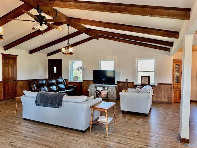 living area featuring a wainscoted wall, lofted ceiling with beams, wood finished floors, and a ceiling fan