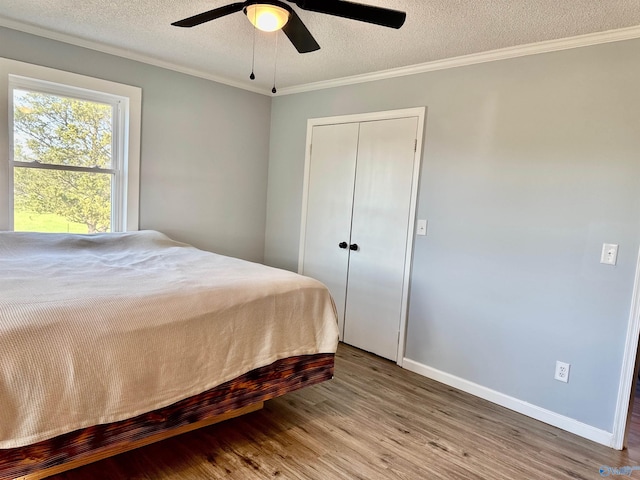 bedroom with ornamental molding, baseboards, a textured ceiling, ceiling fan, and wood finished floors