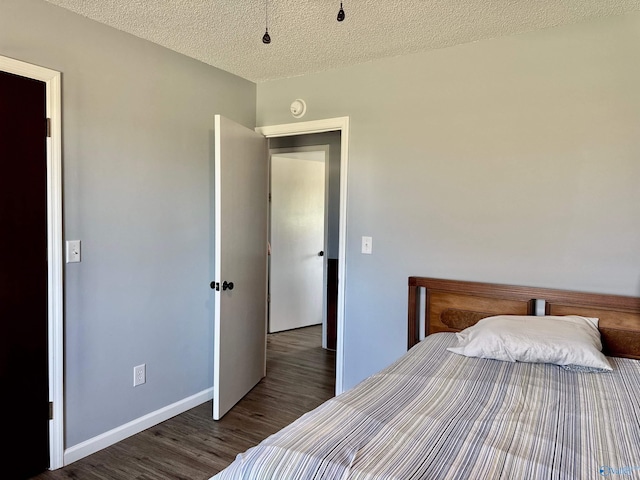 bedroom featuring a textured ceiling, baseboards, and wood finished floors