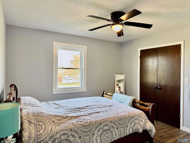 bedroom featuring a closet, a textured ceiling, wood finished floors, and ceiling fan