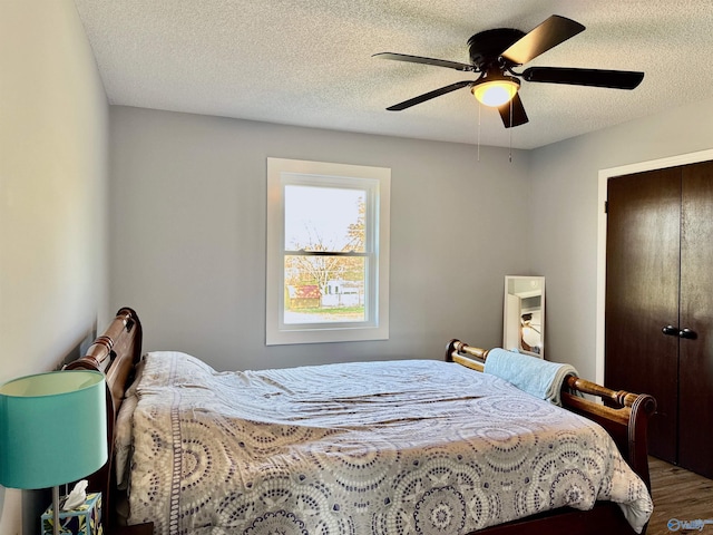 bedroom with a closet, a textured ceiling, wood finished floors, and a ceiling fan