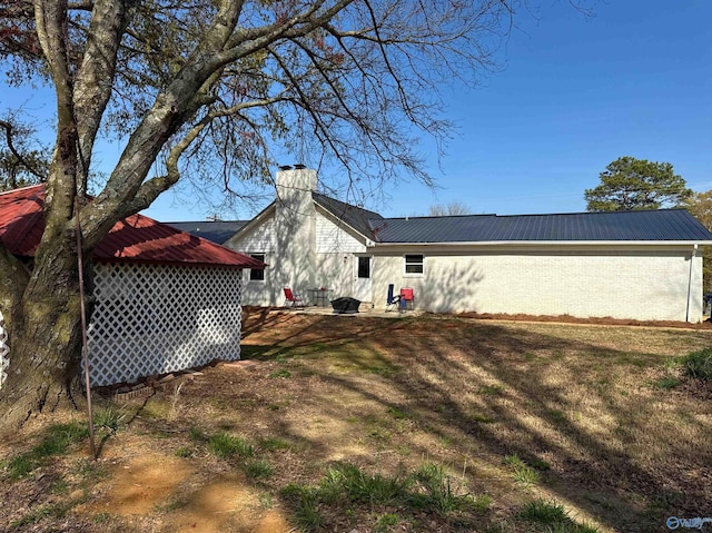 view of side of property with a chimney, a yard, and metal roof