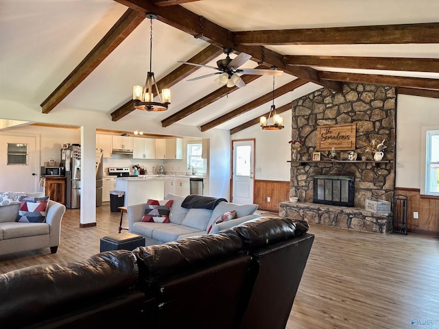 living room featuring wood finished floors, ceiling fan with notable chandelier, and wainscoting
