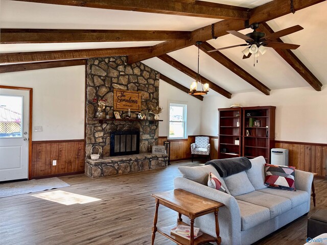 living area featuring wood finished floors, lofted ceiling with beams, a fireplace, and wainscoting