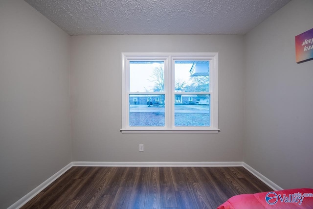 unfurnished room with dark hardwood / wood-style flooring and a textured ceiling