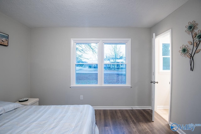 bedroom with a textured ceiling and dark wood-type flooring