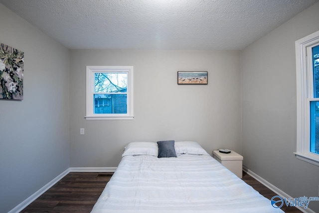 bedroom with dark hardwood / wood-style floors and a textured ceiling