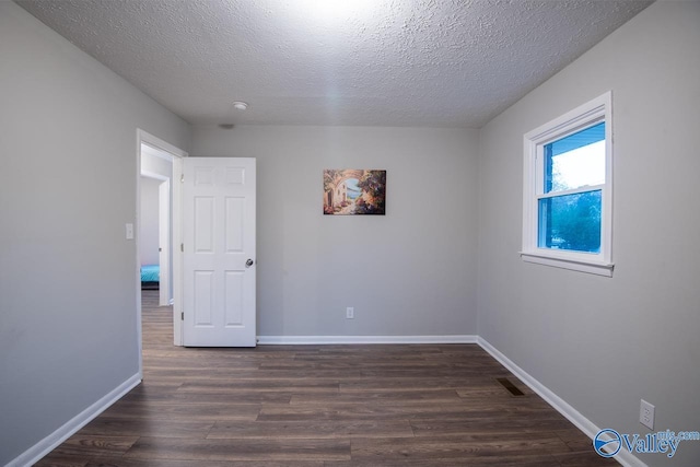 unfurnished room featuring dark hardwood / wood-style floors and a textured ceiling