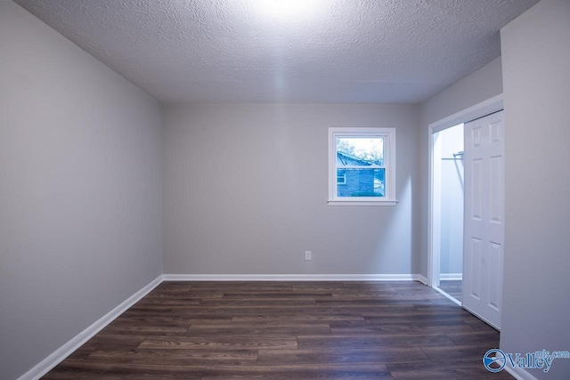 unfurnished bedroom with a textured ceiling and dark hardwood / wood-style flooring