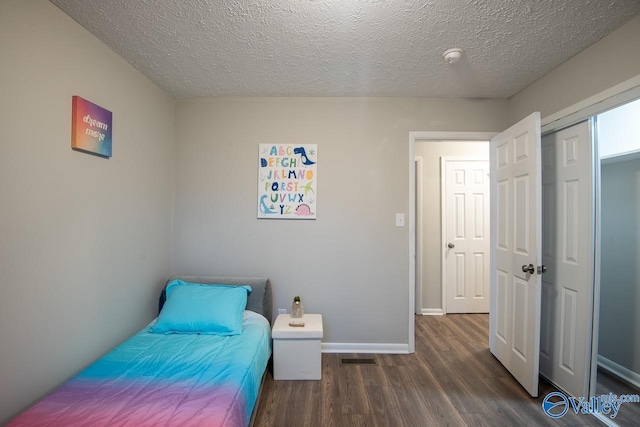 bedroom featuring a closet, dark hardwood / wood-style floors, and a textured ceiling