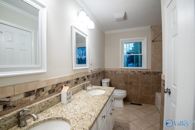 bathroom featuring tile patterned floors, ornamental molding, a textured ceiling, and tile walls