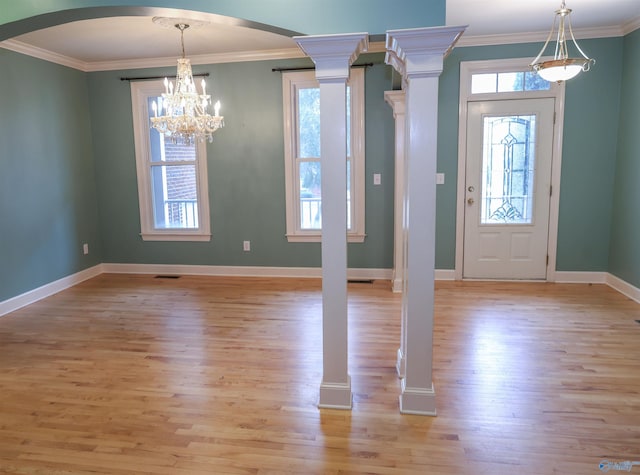 entrance foyer featuring light hardwood / wood-style flooring, an inviting chandelier, a wealth of natural light, and ornamental molding